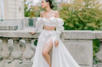 an exquisite and romantic bridal look with an off the shoulder crop top with a draped bodice, an A-line skirt with thigh high slit and a train