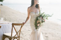 an ivory mermaid wedding dress with a lace embellished bodice, a tulle layered skirt and a train