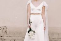 an ultra-modern bridal look with a plain silk crop top with a deep V-neckline and a tulle capelet, high waisted wideleg silk pants and nude shoes