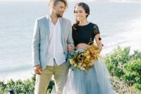 bold wedding attire – a grey blazer, a white shirt and tan pants, a black lace crop top, a grey layered maxi skirt and a bold yellow bouquet