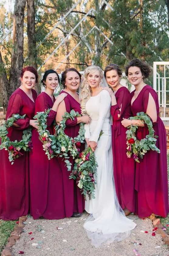 burgundy maxi bridesmaid dresses with deep V-necklines and eye-catchy long sleeves with cutouts for a bright lookat a fall wedding