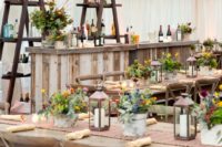 candle lanterns and colorful potted blooms for rehearsal dinner decor with a rustic feel