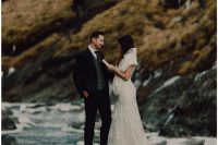 elegant wedding outfits with a black suit, a grey waistcoat and burgundy tie for the groom, a refined lace mermaid wedding dress with a train for the bride