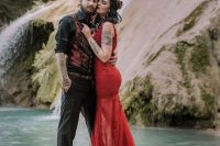a bold informal groom’s look with a black shirt and black pants, a red pritned waistcoat and cuffed sleeves that show off the tattoos