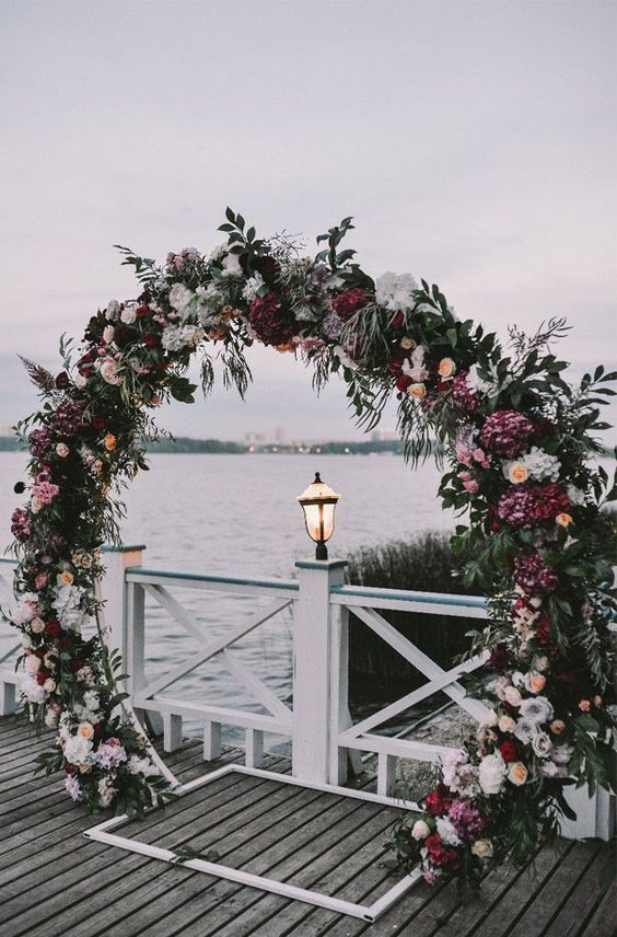 a bright round wedding arch with greenery, white, pink, purple and deep purple blooms is a lovely idea