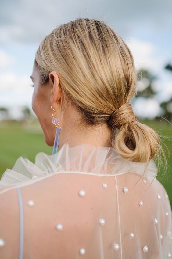 a casual low knot updo with a messy top is a cool idea for a modern or minimalist bride