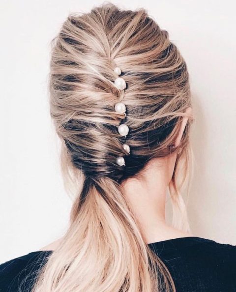 a catchy low ponytail with a twist and several pearl pins for a modern bride-to-be