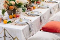 a chic garden rehearsal picnic with neutral and bright textiles, bright blooms, citrus, potted cacti and candle lanterns