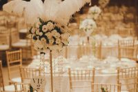a chic neutral table setting in 1920s style, with a tall white rose centerpiece with feathers, candles and pearls and white place settings