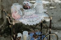 a chic vintage candy bar with an elegant vintage cart, a doily, candles, blooms and a sign for decor