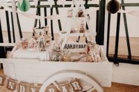 a chic white candy bar of a cart, banners, paper pompoms, lots of candies in jars is a very chic idea