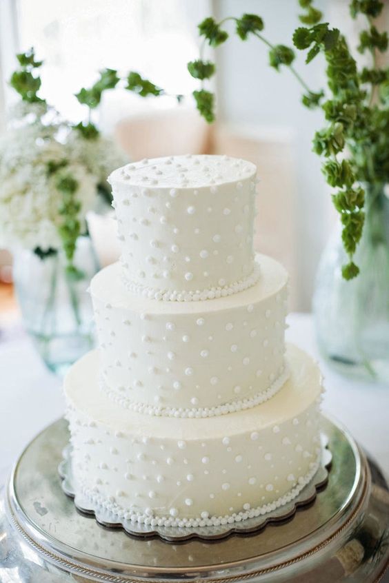 a classy white wedding cake with dimensional polka dots and beads is a lovely idea for a modern neutral wedding