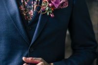 a colorful groom’s look with a blue three-piece pantsuit, a colorful floral shirt and a bold orchid boutonniere, a bold hand tattoo