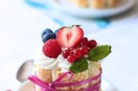 a cookie tower filled with whipped cream, topped with strawberries, blueberries, raspberries and some fresh berries