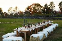 a cool bbq rehearsal with uncovered tables, hay with fur on top for sitting, colorful blooms and neutral linens