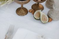 a creative cluster wedding centerpiece of vintage bowls with figs, nuts, a tropical protea and some candles