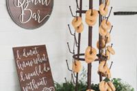 a creative metal stand with hooks, lots of greenery and blooms, fresh donuts and a sign with calligraphy
