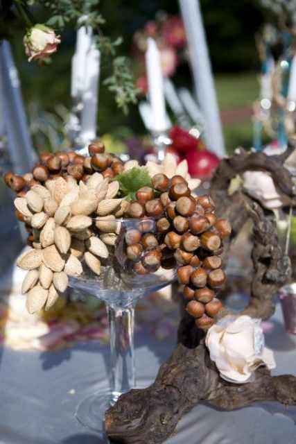 a creative wedding centerpiece of a glass bowl filled with various nuts and driftwood is amazing for a wedding