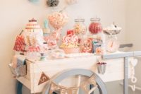 a cute vintage cart candy bar with banners, a sign, lots of tasty candies served in jars, on stands and in bowls