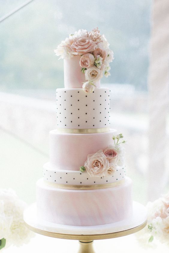 a delicate wedding cake with pink marble and black and white polka dot tiers, white and blush blooms is a chic and refined dessert for a blush wedding