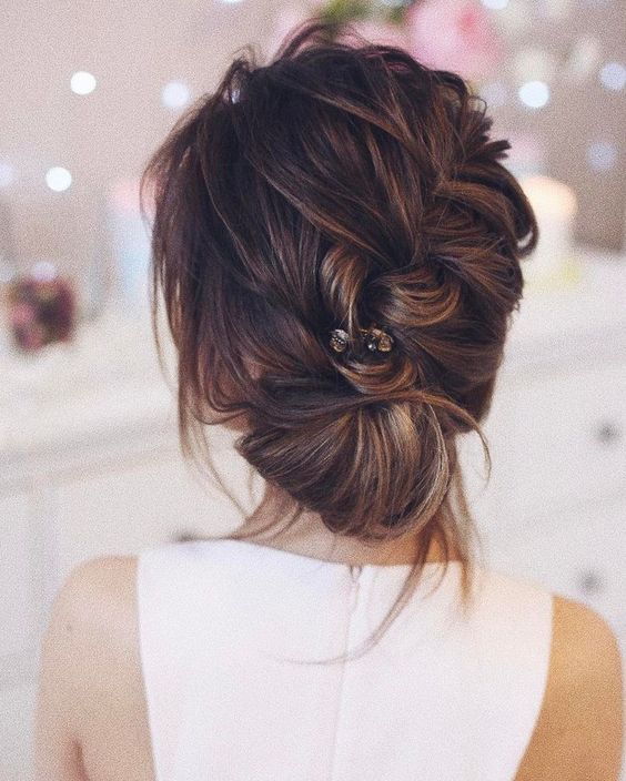 a diagonal braided updo with a low bun, some locks down and a little hairpiece