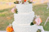 a dusty blue wedding cake with dimensional polka dots, bright blooms, seed pods and greenery is amazing for a spring or summer wedding