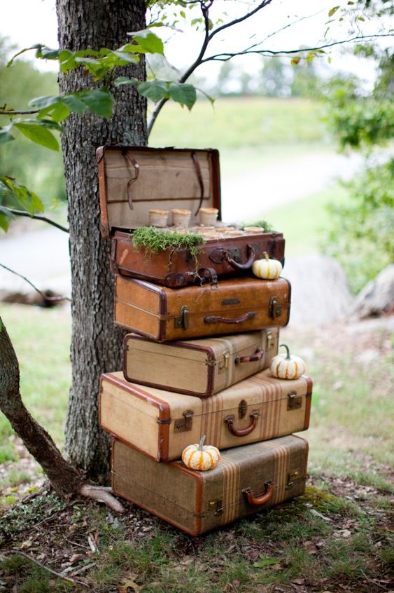 a fall wedding decoration of a stack of vintage suitcases, mini pumpkins, moss and souffle inside the suitcase can be easily realized