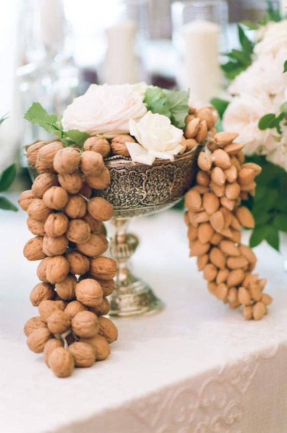 a fantastic wedding centerpiece of a vintage silver bowl, with lots of nuts and white blooms and greenery on top