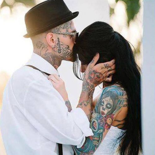 a fully tattooed groom with a cuffed shirt that shows off ihs arm tattoos and tattooed face