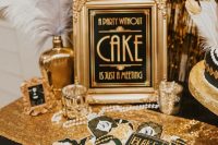 a glam gold and black dessert table with feathers, candles, pearls, sparkles, a sign and some themed cookies on a gold tray