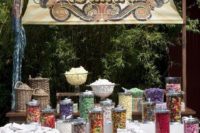 a large candy bar with a table, an oversized bright sign and lots of colorful candies in large jars