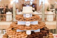 a large cookie stand with toppers and a wedding cake on top is a chic idea for any wedding
