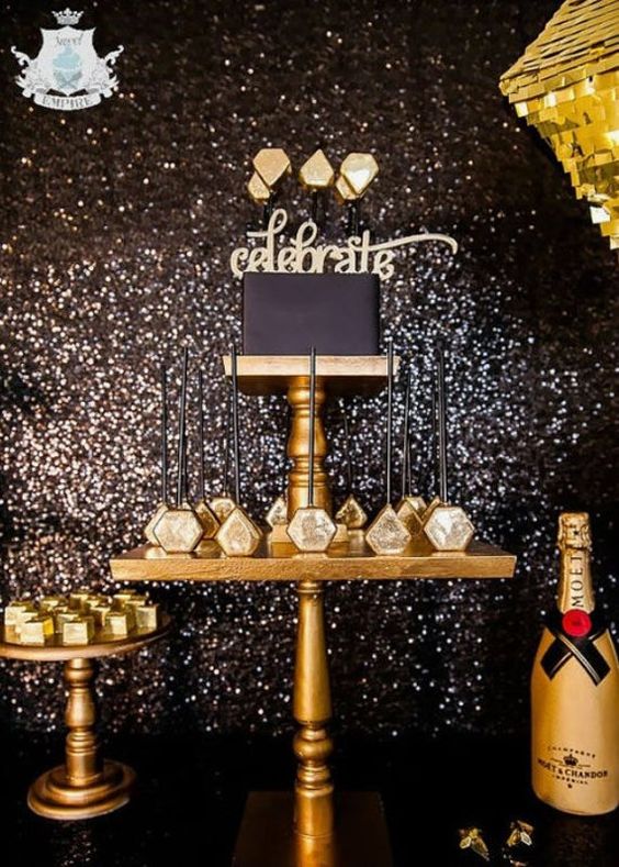 a lovely glam black and gold dessert table with a black cake, gold desserts and a black sequin backdrop is amazing