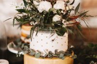 a lovely wedding cake with a gold tier, a white and gold polka dot tier, greenery, white blooms and a calligraphy topper is amazing