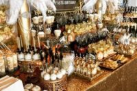 a luxurious art deco candy bar with lots of sweets, feathers, beads and embellishments plus a gold sequin tablecloth
