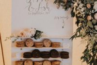 a mini cookie wall with various type sof sweets and fresh blooms and greenery for a romantic touch