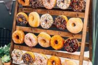 a mini wooden stand with metal hooks and glazed donuts is a super cute idea for a rustic wedding