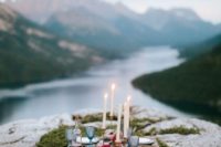 a mountain rehearsal dinner picnic with a pallet table, candles, blue glasses and porcelain plus a gorgeous view