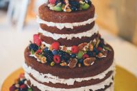 a naked chocolate wedding cake with cream cheese froting, fresh berries, greenery and nuts is a great idea for a rustic wedding