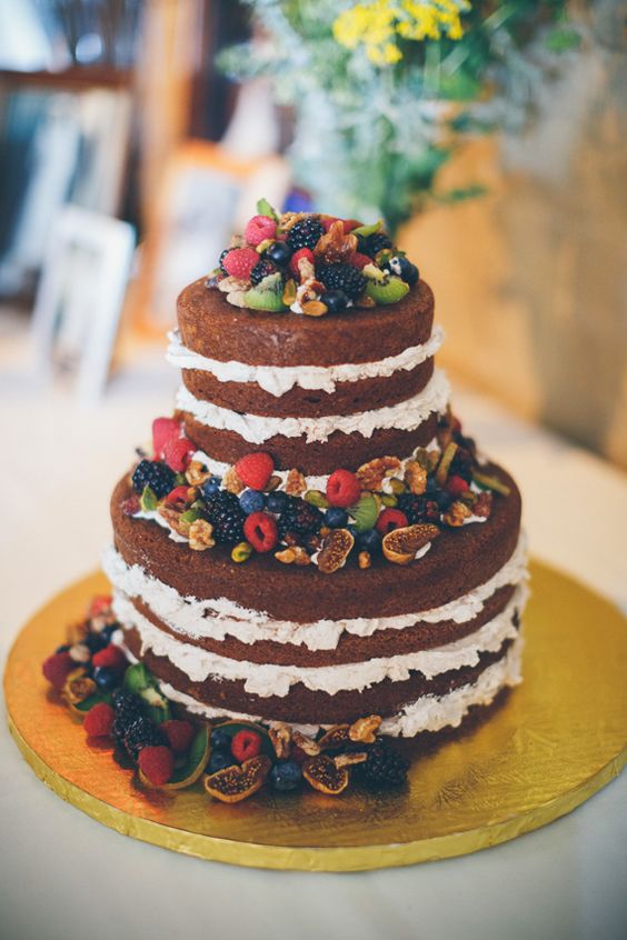 a naked chocolate wedding cake with cream cheese froting, fresh berries, greenery and nuts is a great idea for a rustic wedding