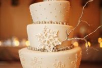 a neutral winter wedding cake with metallic beads, a polka dot, plain and snowflake tier, sugar snowflakes and a metallic branch