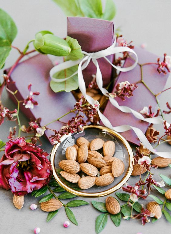 a porcelain plate with gold rims and almonds will show your guests what you packed into pink paper bags as wedding favors