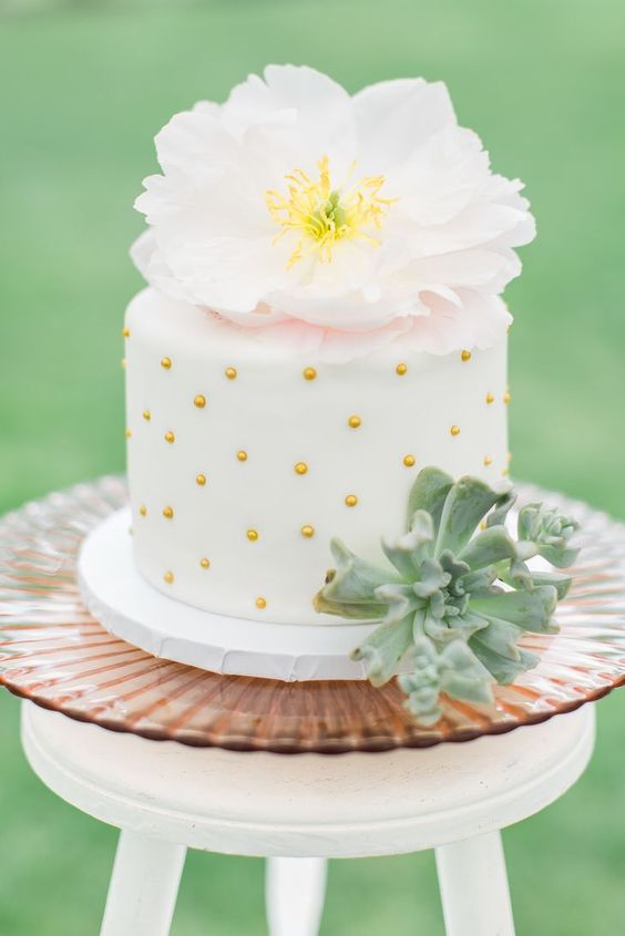 a pretty glam wedding cake in white, with dimensional polka dots, a succulent, a large neutral bloom on top is amazing for spring or summer