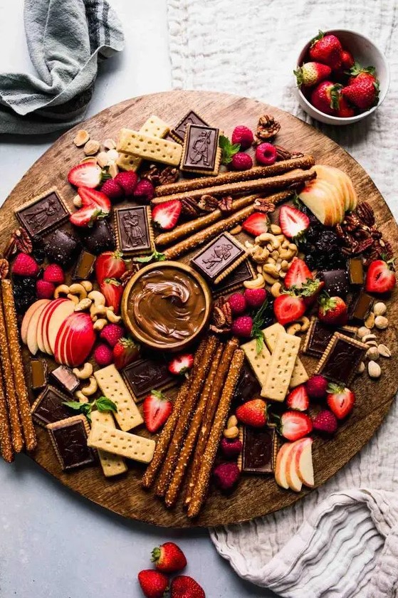 a refined dessert board with various cookies, apples, strawberries, raspeberries, chocolate and chocolate dip, nuts is amazing for a wedding
