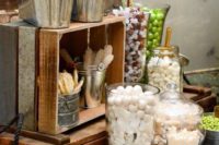 a rustic candy bar with crates, metal buckets, wood slice stands and jars with candies