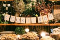 a rustic wedding cookie bar with burlap banner, wood stumps with plates wit cookies and candles around