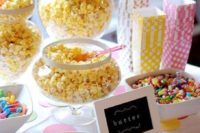 a small and cute popcorn bar with popcorn in glass jars, sprinkles and candies and colorful paper bags