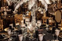 a sophisticated 1920s tablescape with a black sequin tablecloth, gold chargers and black napkins, a tall feather centerpiece