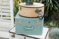 a stack of delicate neutral vintage suitcases topped with a floral arrangement with greenery and berries is a lovely spring or summer decoration