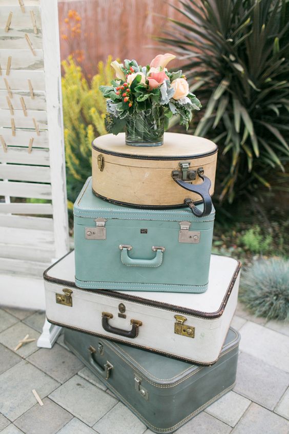 a stack of delicate neutral vintage suitcases topped with a floral arrangement with greenery and berries is a lovely spring or summer decoration